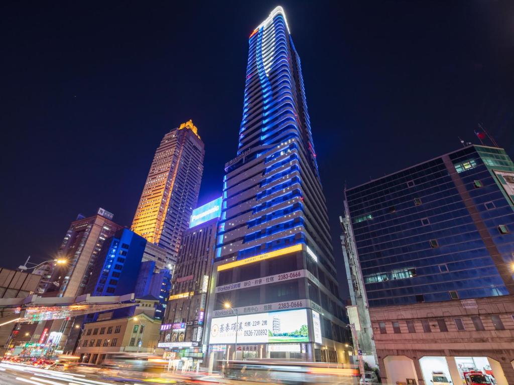 a tall skyscraper in a city at night at Roaders Plus Hotel - Taipei Station in Taipei