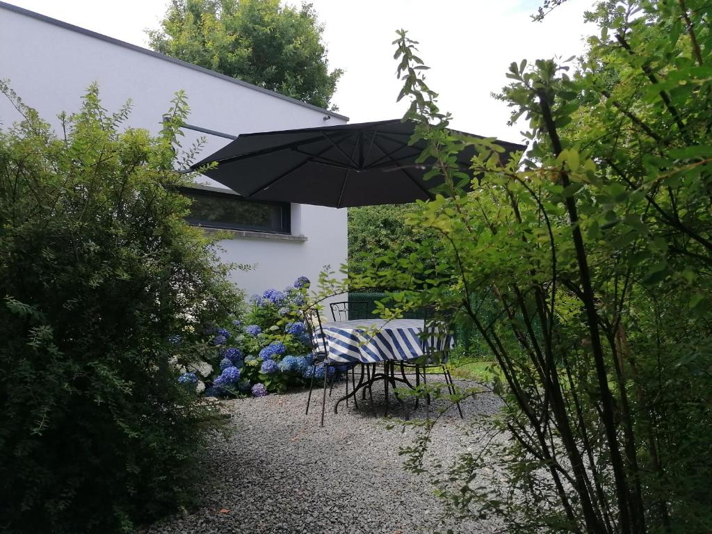 a table and chairs under an umbrella in a garden at Chambres d&#39;hotes Grace in Guérande