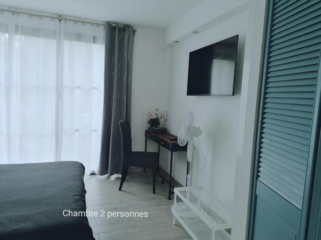 a bedroom with a desk and a window with a television at Chambres d&#39;hotes Grace in Guérande