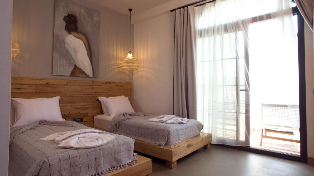 a bedroom with two beds and a large window at Dmira Alacati in Alaçatı