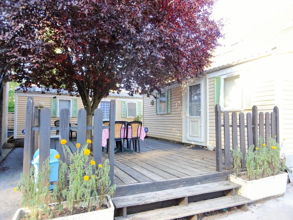 eine Holzveranda mit einem Holzzaun und einem Baum in der Unterkunft Mobil-Home 2 "Camping" in Pesmes