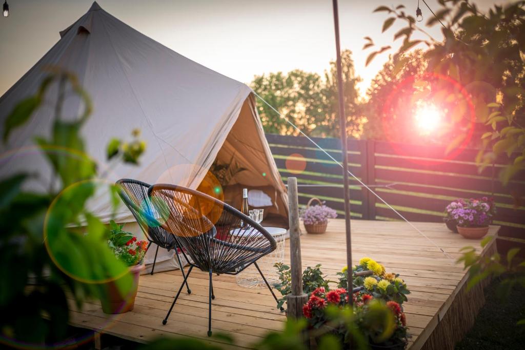 a tent on a deck with a chair and flowers at Pokoje u Basi Glamping Mikołajki in Mikołajki