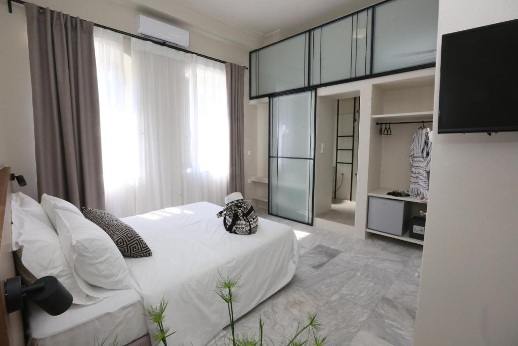 a bedroom with a white bed and a large window at OIKO MINI SUITES in Ermoupoli