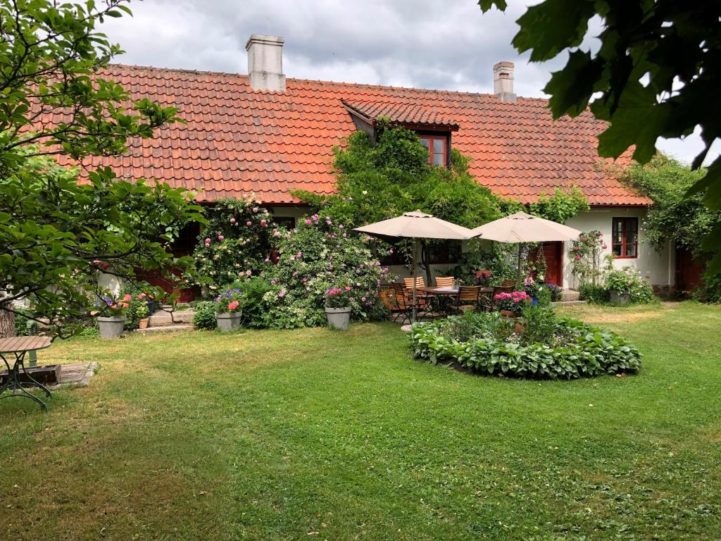 a house with a yard with umbrellas and flowers at Mariehem Logi in Sjöbo