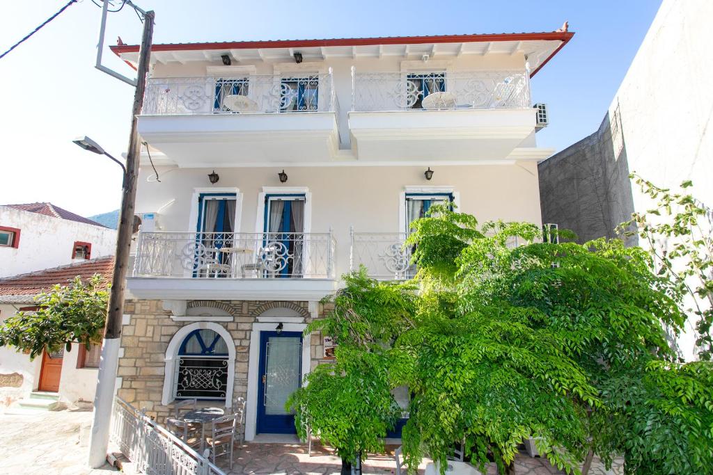 a white house with blue windows and a balcony at The Old Town hall in Parga