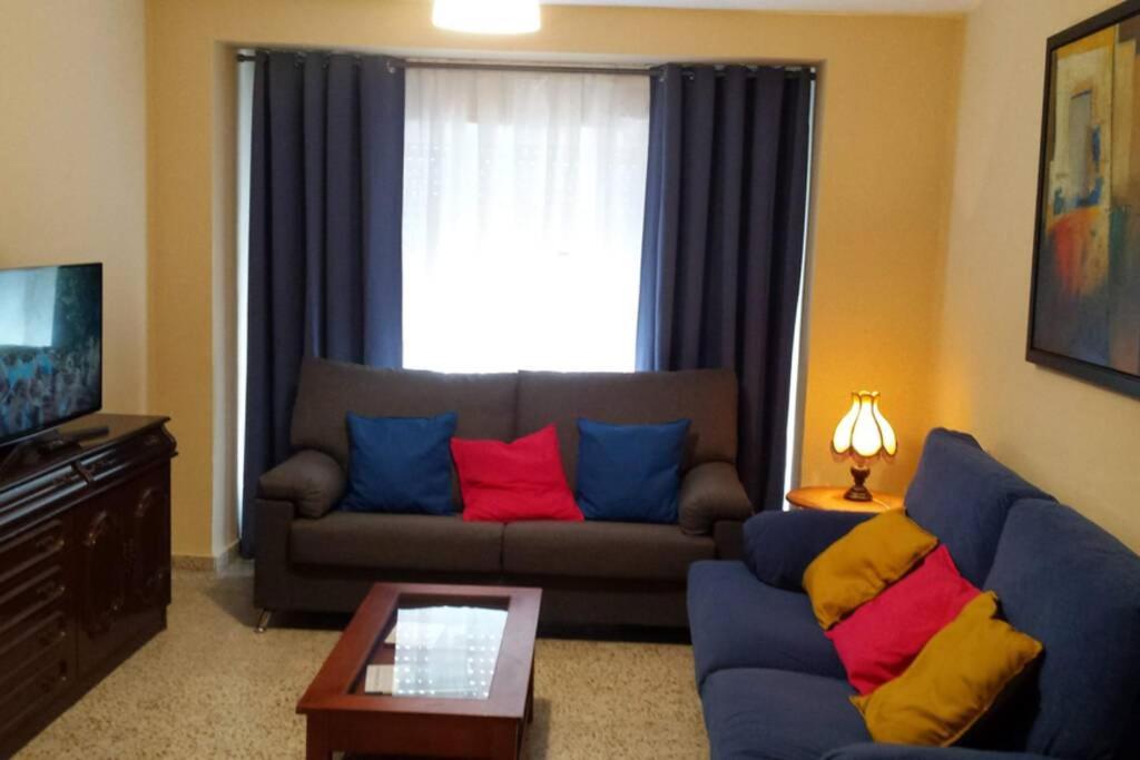 a living room with a blue couch with colorful pillows at Apartamentos Campomanes 2 in Campomanes