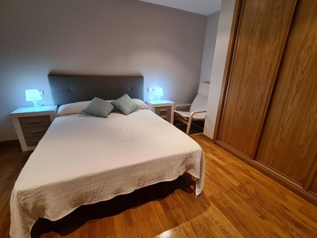 1 dormitorio con 1 cama grande y 1 silla en APARTAMENTOS VIVE en Viveiro