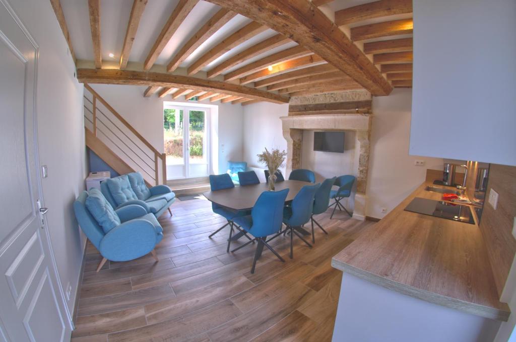 a living room with a dining room table and blue chairs at Au pré des acajous in Pertheville-Ners