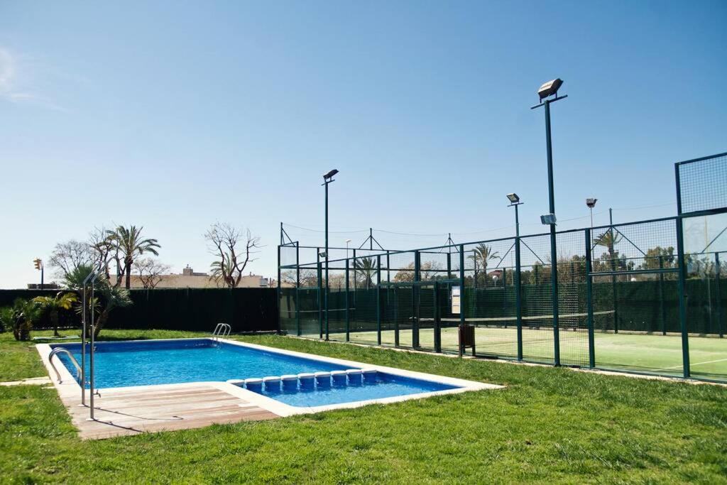 ein Pool auf einem Tennisplatz neben einem Tennisplatz in der Unterkunft Apartamento diseño a cien metros del mar. in Torredembarra