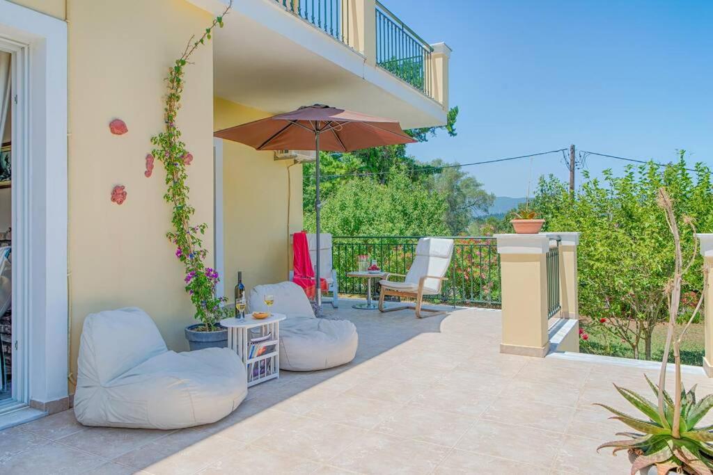 a patio with two white chairs and an umbrella at Villa Aglaia in Corfu