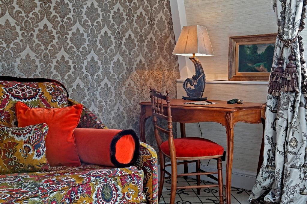 a living room with a chair and a table with a lamp at Relais Christine in Paris