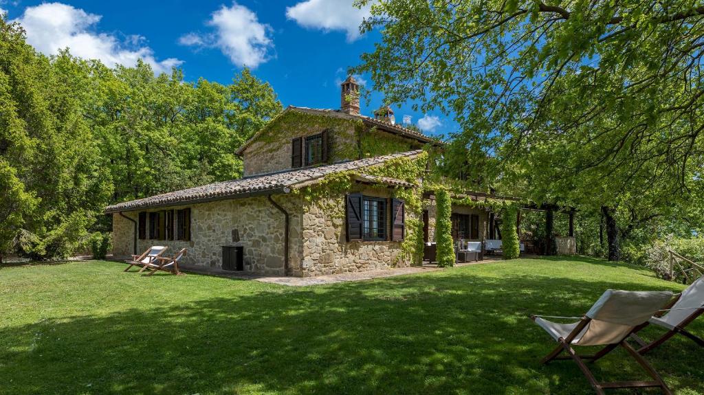 una antigua casa de piedra con sillas en un patio en LA CERQUA 8, Emma Villas, en Gualdo Cattaneo