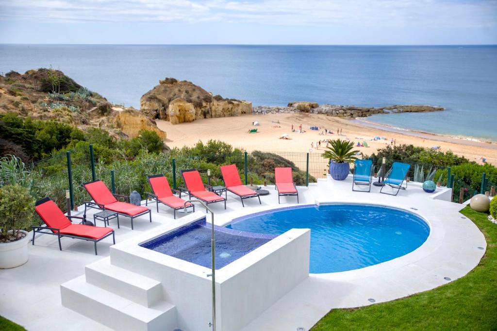 una piscina con sillas y una playa de fondo en Luxurious BEACHFRONT VILLA de la PLAGE with private beach acces, en Albufeira
