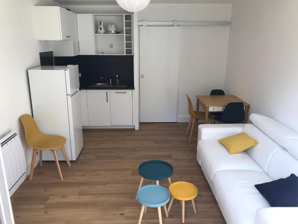 a living room with a white couch and some chairs at Studio Les Pétrels avec terrasse et jardinet à 2 pas de la plage in Pornichet