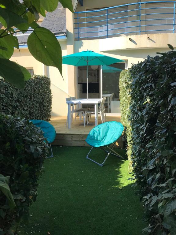 une terrasse avec 2 chaises et une table avec un parasol dans l'établissement Studio Les Pétrels avec terrasse et jardinet à 2 pas de la plage, à Pornichet