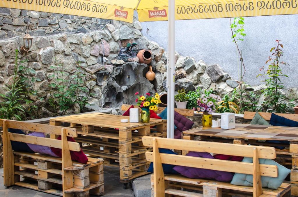 un patio con mesas y sillas de madera y una sombrilla en Light House Old City en Akhaltsikhe