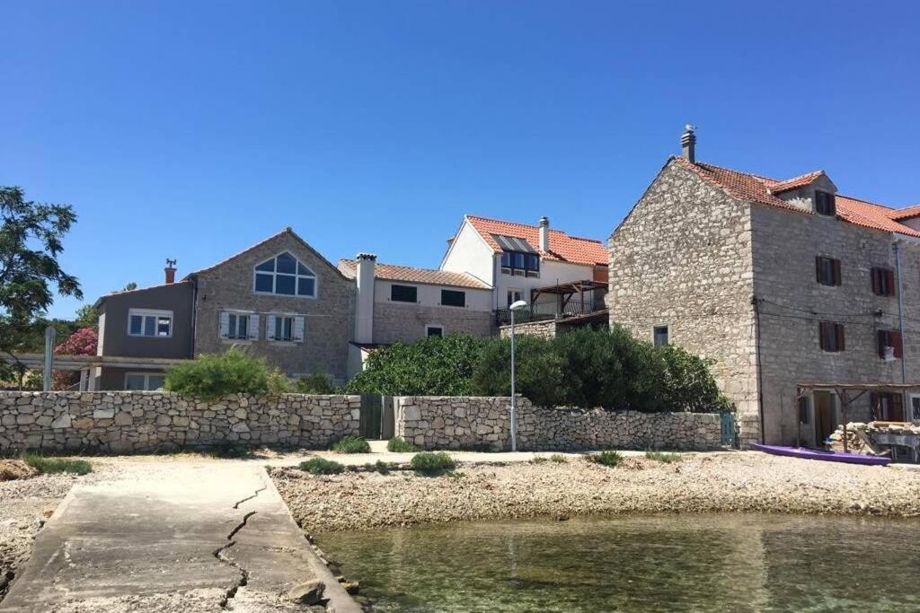 a large stone building next to a body of water at Heritage Stone House by the Sea in Prvić Šepurine