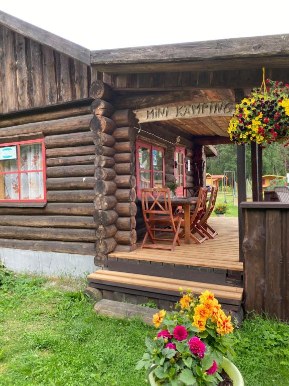 Cabaña de madera con mesa y sillas en el porche en Mini Camping, en Kabli
