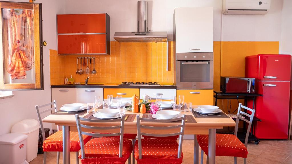 a kitchen with a wooden table with chairs and a red refrigerator at Welcomely - L'Alzoni in San Teodoro