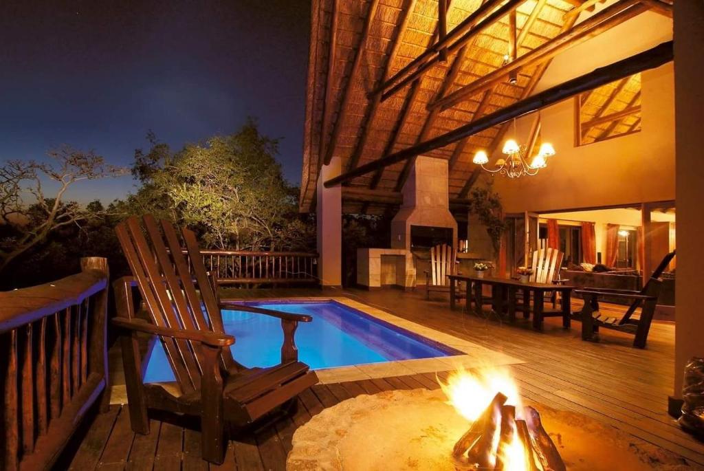 a swimming pool with a chair and a table at Mingwe Private Game Lodge in Mabula