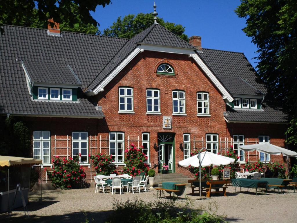 a large red brick building with tables and chairs at Hof Osterbunsbüll in Mittelangeln