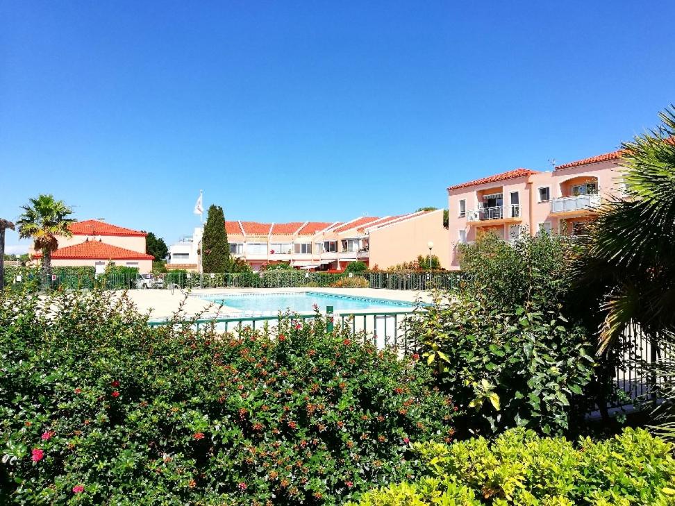 a view of a swimming pool in a resort at Appartement La pinède - Tout Confort - Piscine de saison - 2 chambres - Proche plage et Commerces in Le Barcarès