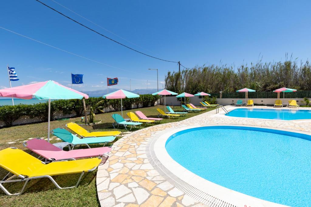 a pool with chairs and umbrellas next to a resort at Villa Amorossa with Garden View & Shared Pool by Konnect, Roda Corfu in Roda