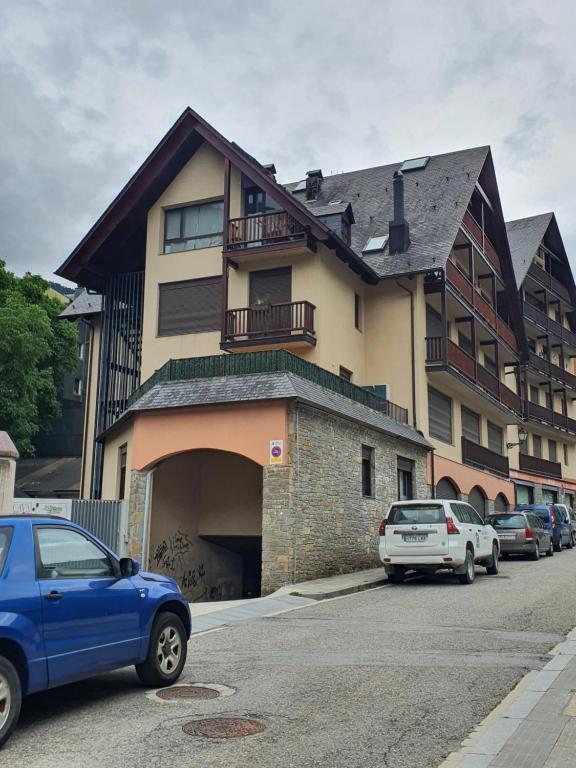 une voiture bleue garée devant un bâtiment dans l'établissement VIELHA XVI, à Vielha e Mijaran