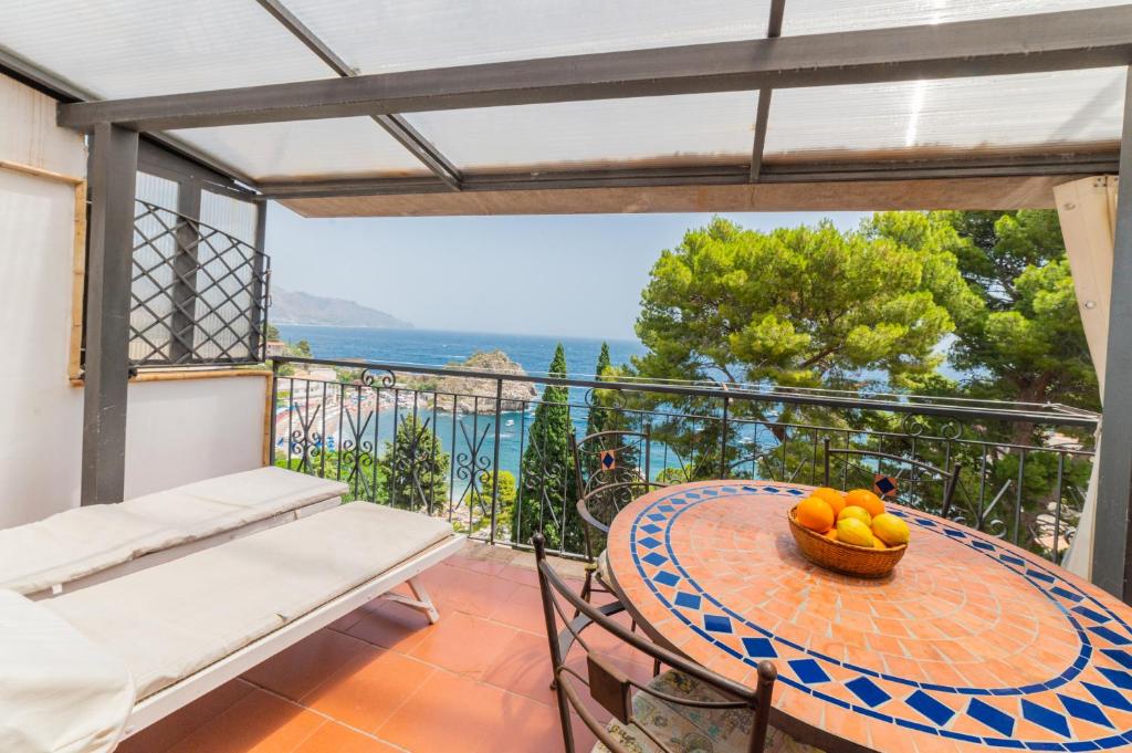 a table and chairs on a balcony with a bowl of fruit at ToviMar Apartments in Taormina