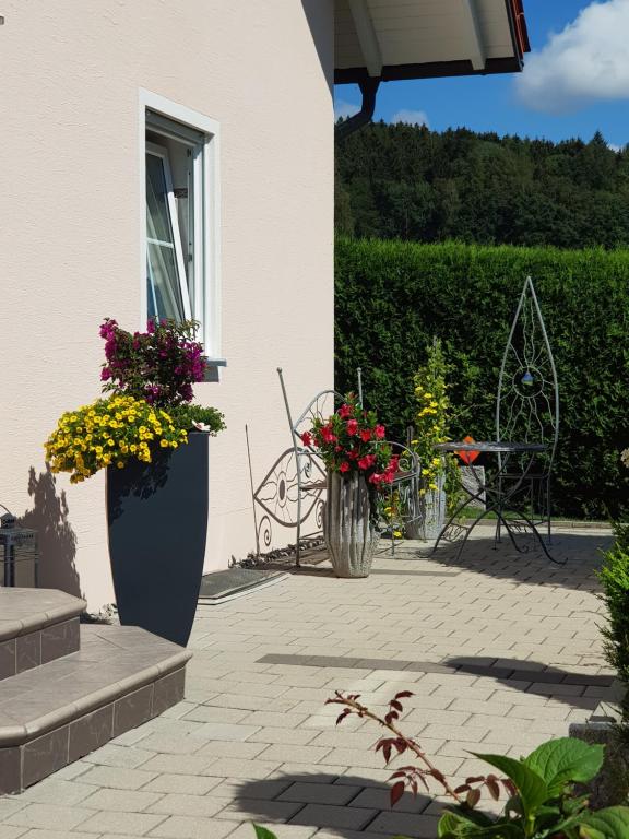 a patio with a table and chairs and flowers at Ferienwohnung Toni mit Balkon und Garten in Pemfling