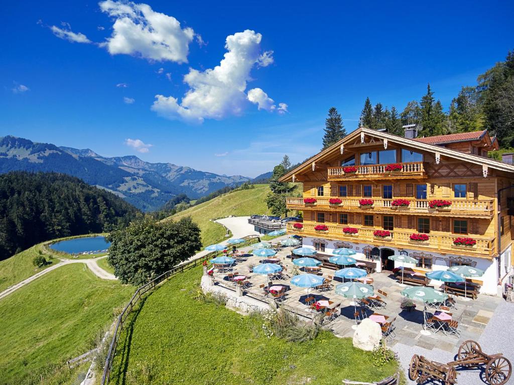 ein Hotel auf einem Hügel mit Tischen und Sonnenschirmen in der Unterkunft Berggasthof Bichlersee in Oberaudorf