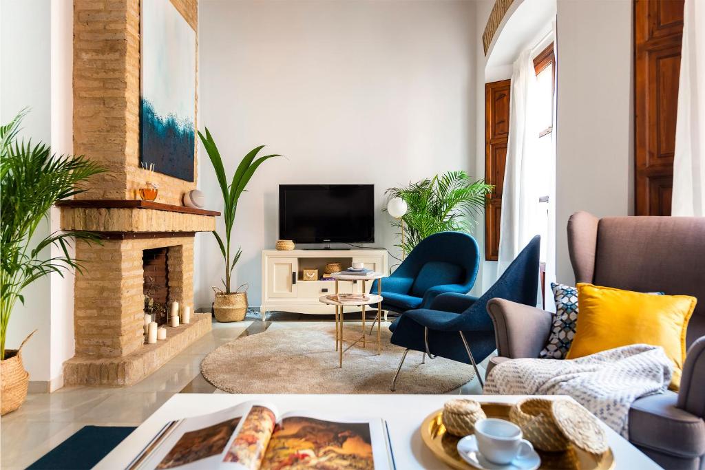 sala de estar con sillas azules y chimenea en Genteel Home Alhóndiga Sevilla, en Sevilla