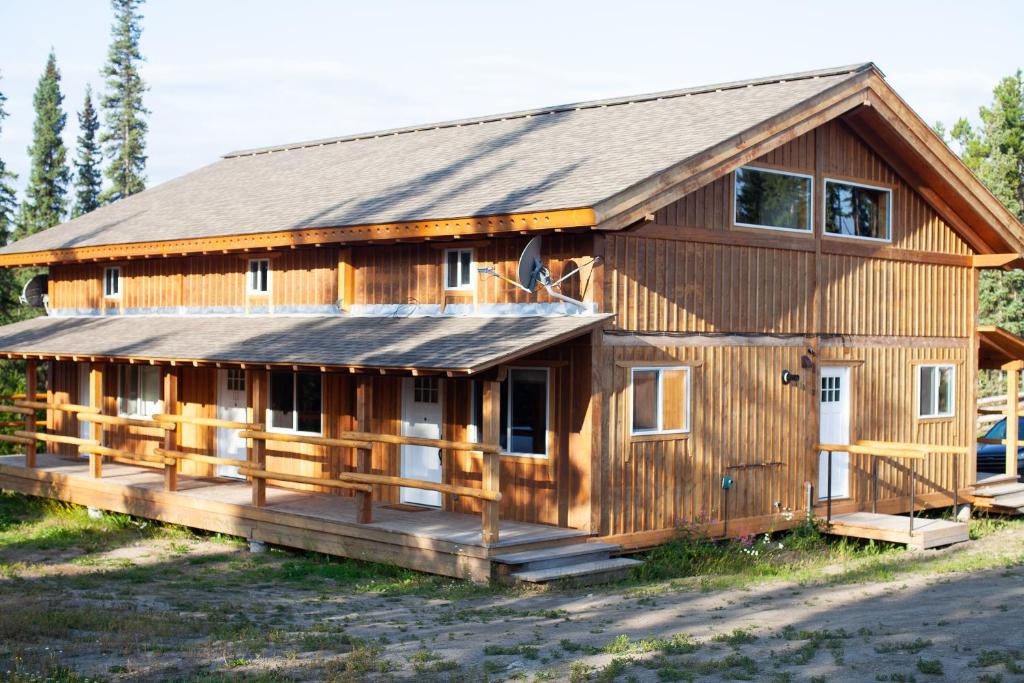 uma grande cabana de madeira com um alpendre em Red Cariboo Apartments em Anahim Lake