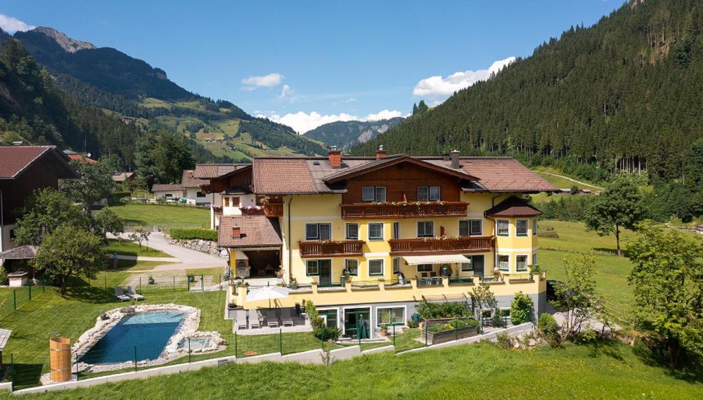 a large house in the mountains with a pool at Landhaus Huber in Grossarl