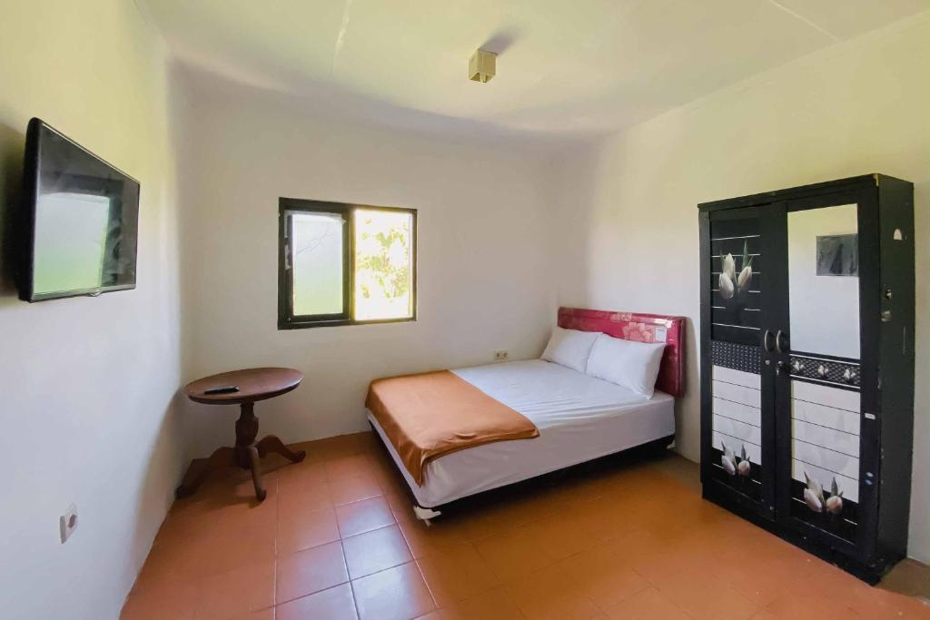a small bedroom with a bed and a table at KoolKost At Tenggilis - Minimum Stay 30 Nights in Tenggilismedjojo