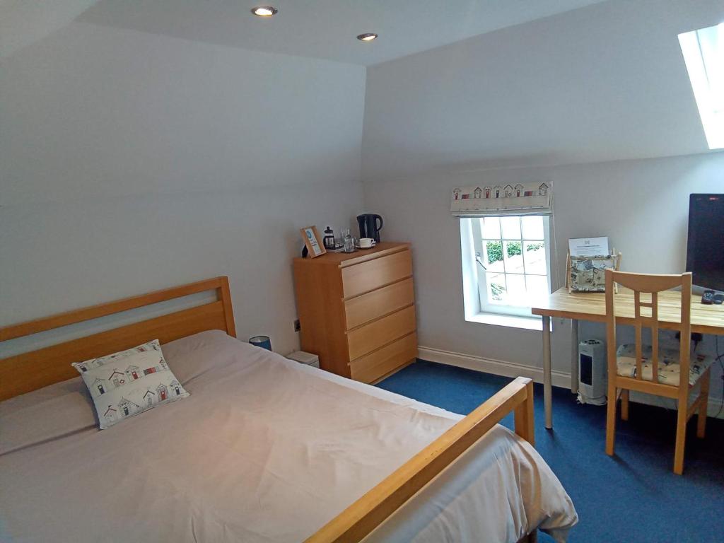 a bedroom with a bed and a desk and a window at The Hayloft in Hornsea