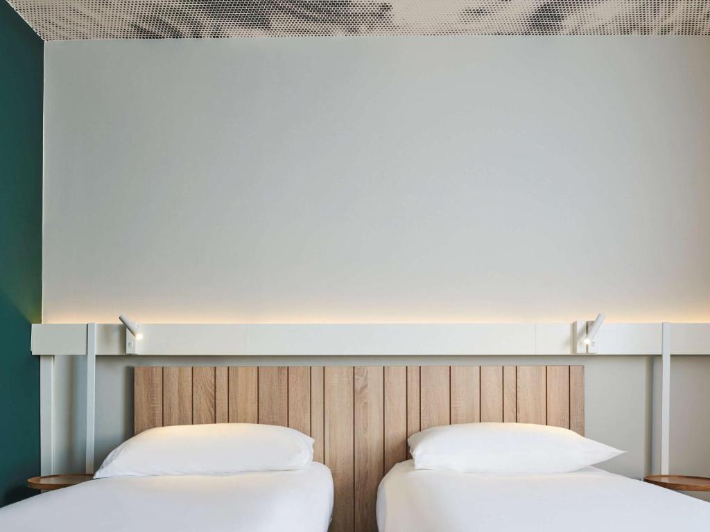 two beds with white pillows sitting next to each other at Ibis Luxembourg Airport in Luxembourg