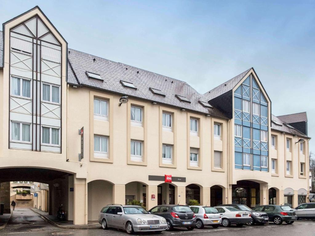 a large building with cars parked in front of it at ibis Alençon in Alençon