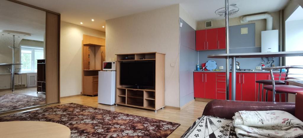 a living room with a kitchen with red cabinets at Apartment On Oktyabrskaya 4 in Ukhta