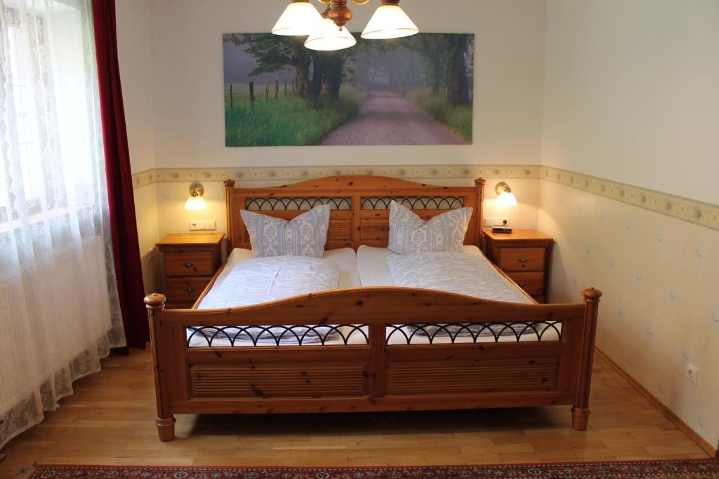 a bedroom with a large wooden bed with two pillows at Kreuzerhof Hotel Garni in Rothenburg ob der Tauber