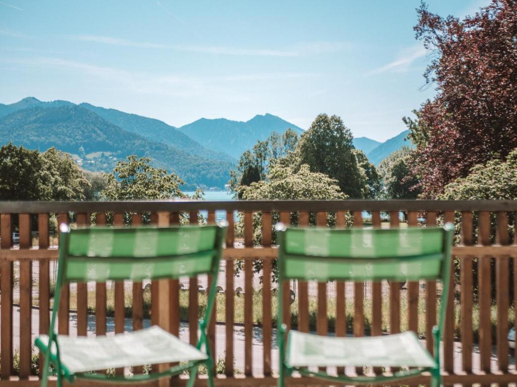 zwei grüne Stühle auf einer Terrasse mit Bergen im Hintergrund in der Unterkunft LEDA AM ECK in Bad Wiessee