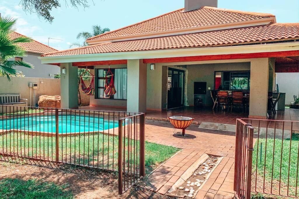 a house with a swimming pool in front of a house at Pecanwood Golf Estate Home - Hartbeespoort in Hartbeespoort
