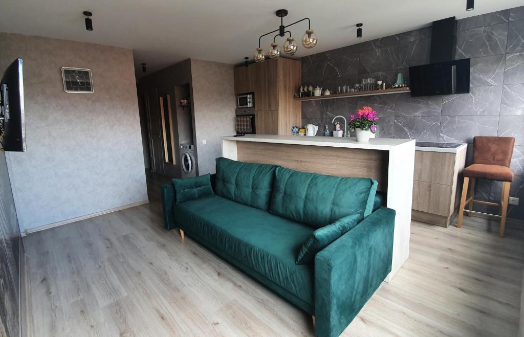 ein Wohnzimmer mit einer grünen Couch in einer Küche in der Unterkunft Dzintaru apartaments in Liepāja