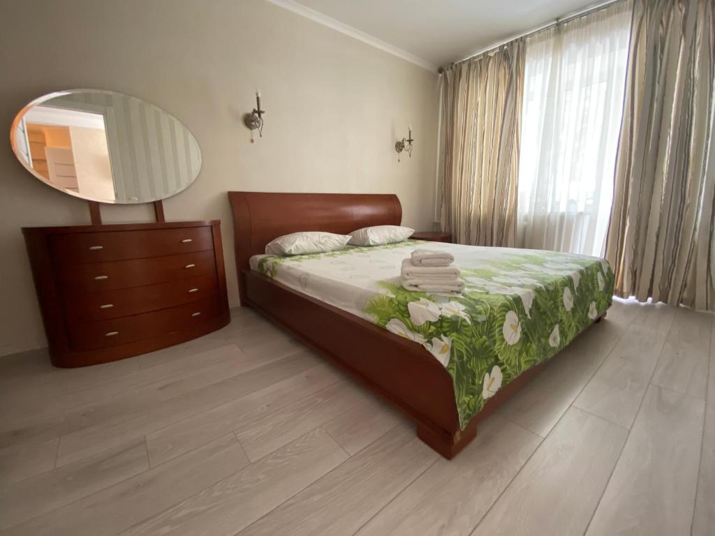 a bedroom with a bed with a dresser and a mirror at Apartment on Prospiekt Pobiedy 18 in Kyiv