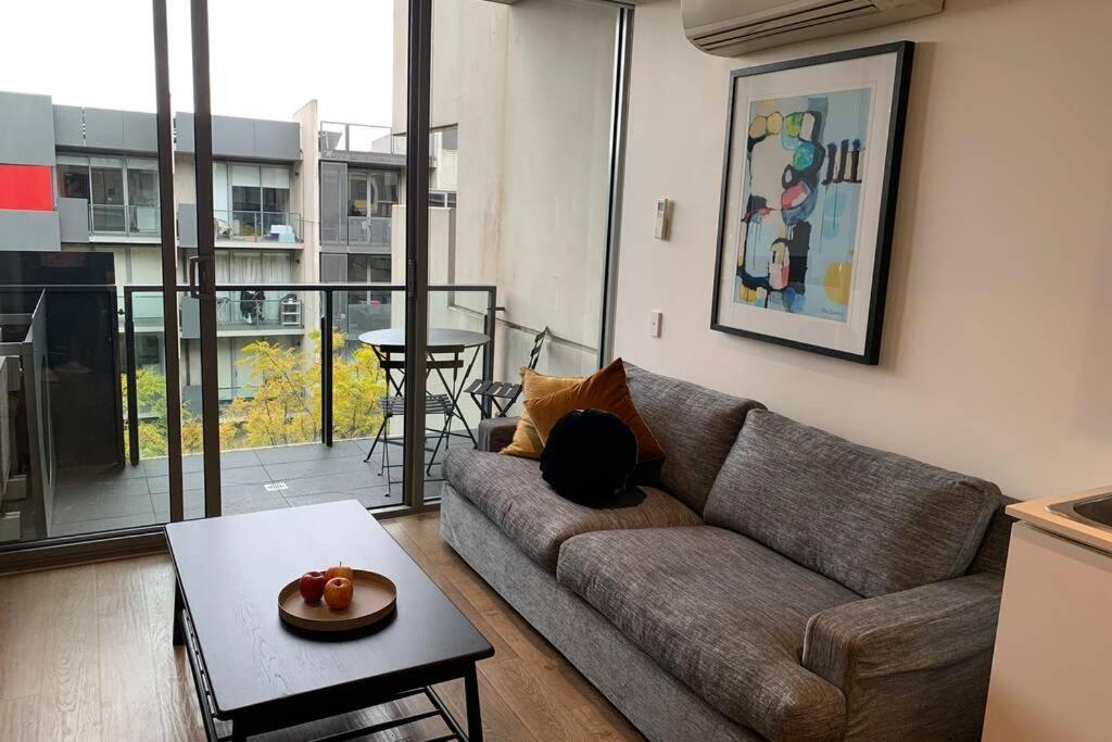 Sunny Balcony Over a Calm Private Garden في ملبورن: غرفة معيشة مع أريكة وطاولة