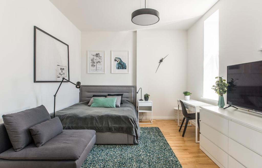 a bedroom with a bed and a couch and a desk at Cozy Modern Studio in City Centre & QueenSize Bed in Rīga