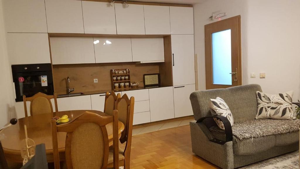a living room with a table and a couch and a kitchen at Redon Apartment in Prishtinë