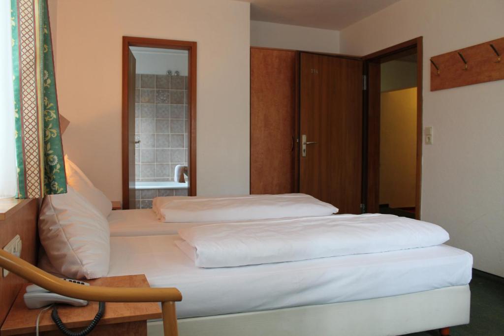 a bedroom with two beds and a chair at Hotel Gasthof zur Linde in Rothenburg ob der Tauber