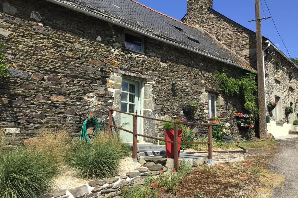 un antiguo edificio de piedra con una puerta blanca en Les Ecuries is a modern renovated barn, en Laniscat