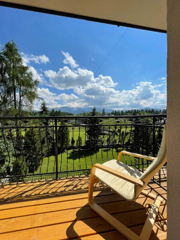 una silla sentada en una terraza con vistas a un campo en Pokoje Gościnne MAGNAS, en Poronin